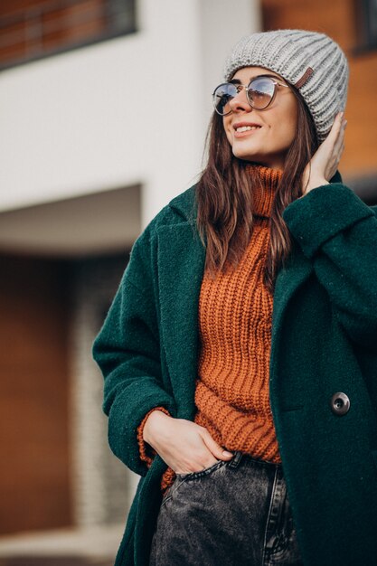 Young woman in coat in winter time by the house