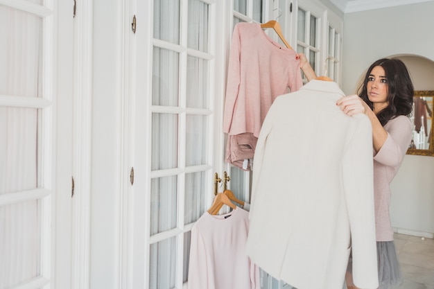 Free photo young woman comparing different garments