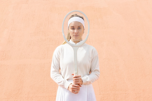 Young woman cover face with tennis racket