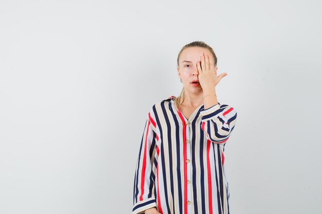 Young woman cover her one eye with her hand in striped blouse and looking beautiful