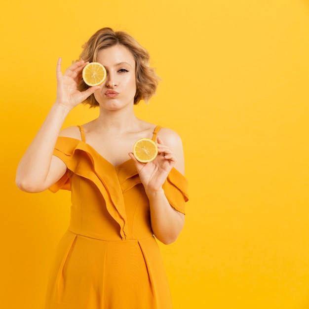 Young woman covering eyes with lemon slices