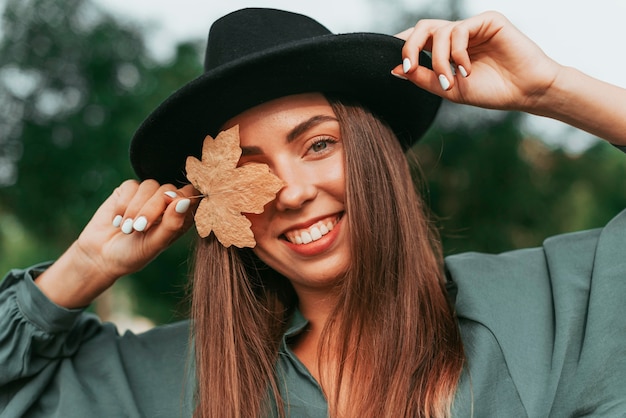 Free Photo young woman covering her eye with a dry leaf