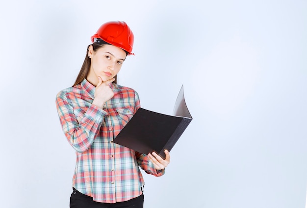 Free photo a young woman in crash helmet making notes in black folder .