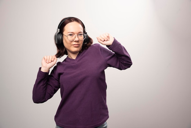 Young woman dancing and listening music in headphones on a white. High quality photo