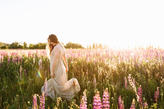 Free photo young woman dancing on a wildflower field with sunrise on the background.