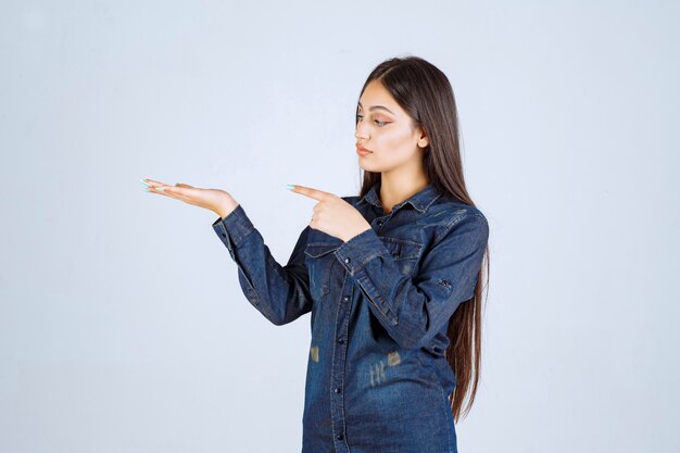 Young woman in denim shirt pointing to the left side