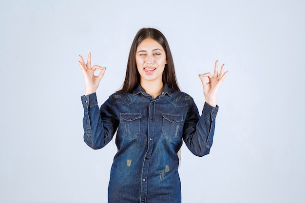 Young woman in denim shirt showing enjoyment sign