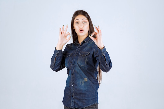 Young woman in denim shirt showing positive hand sign