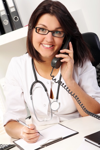 Young woman doctor talking by phone