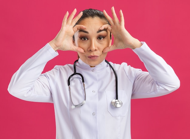 Young woman doctor     wide opening eyes with fingers