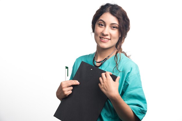 Young woman doctor with clipboard holding pen in her hand on white background. High quality photo