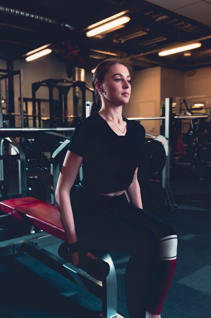 Young woman doing exercise with dumbbell in fitness center