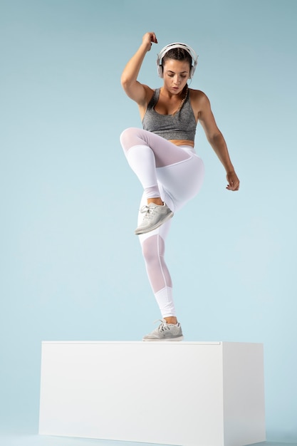 Young woman doing exercises with her headphones on