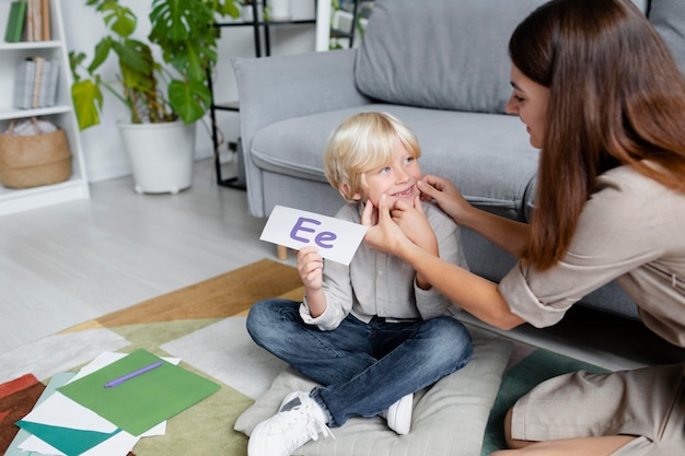 Young woman doing speech therapy with a little blonde boy