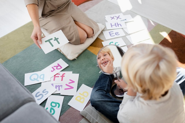 Free Photo young woman doing speech therapy with a little blonde boy