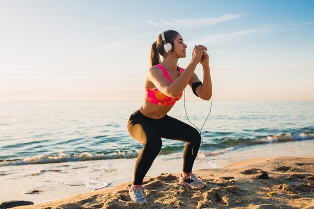 Young woman doing sport exercises on sunrise beach in morning