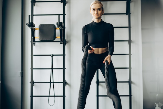 Free photo young woman doing workout with battle ropes