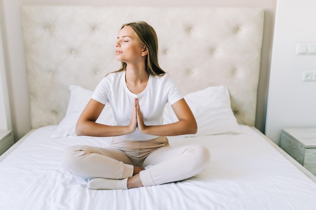 Young woman doing yoga exercises on the bed at home