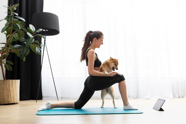 Free photo young woman doing yoga next to her dog