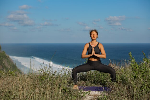 Young woman doing yoga outdoors with amazing back view. Bali. Indonesia.