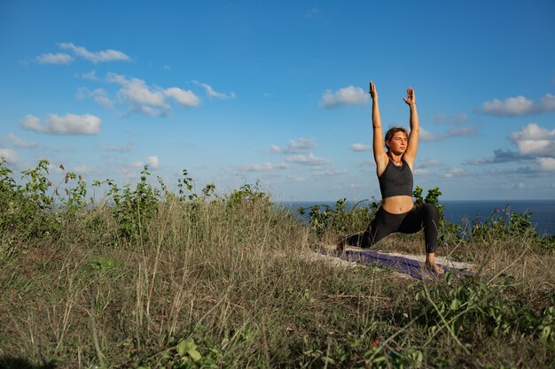 Young woman doing yoga outdoors with amazing back view. Bali. Indonesia.