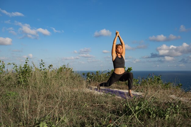 Young woman doing yoga outdoors with amazing back view. Bali. Indonesia.