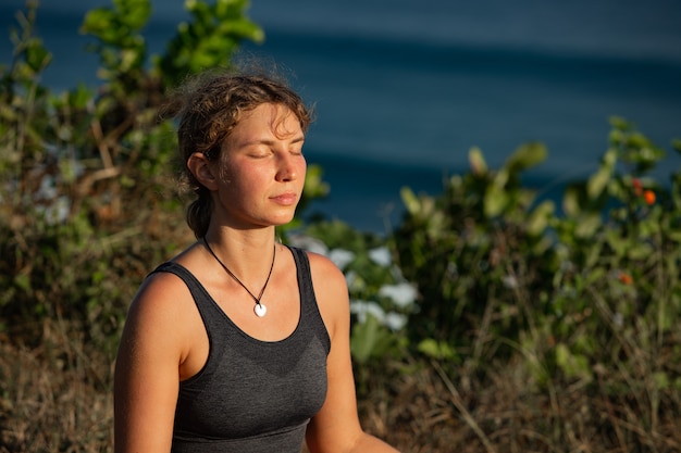 Young woman doing yoga outdoors with amazing back view. Bali. Indonesia.