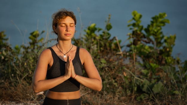 Young woman doing yoga outdoors with amazing back view. Bali. Indonesia.