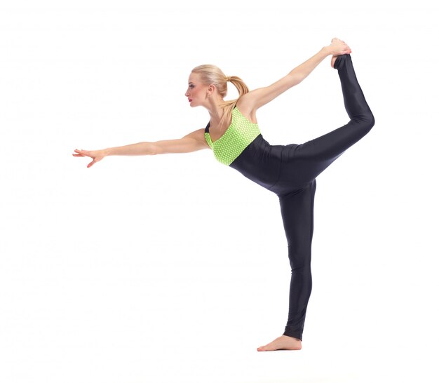 young woman doing yoga on white balancing on one leg