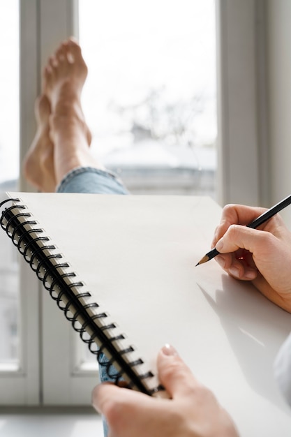 Free Photo young woman drawing at home near the window