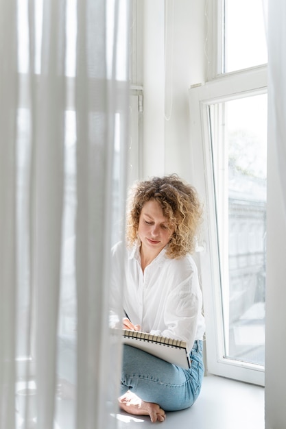 Young woman drawing at home near the window