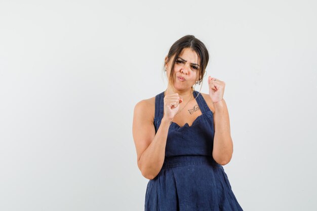 Young woman in dress holding fists raised and looking gloomy