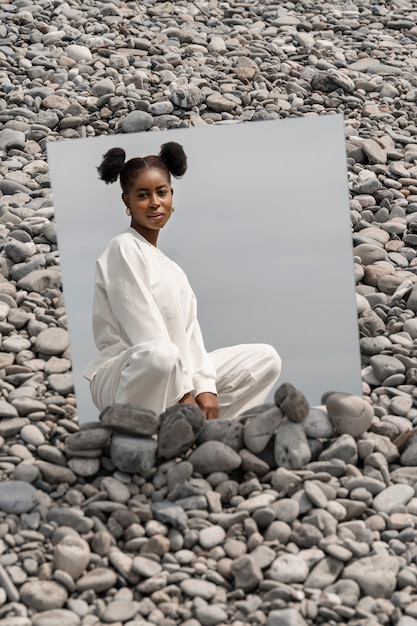 Free Photo young woman dressed in white posing with mirror in rocks