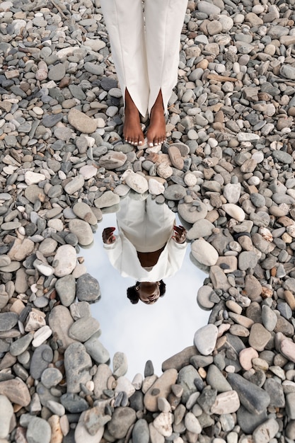 Free Photo young woman dressed in white posing with mirror in rocks