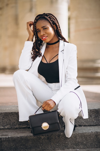 Young woman dressed in white sitting on stairs