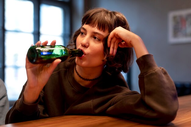 Young woman drinking a beer alone