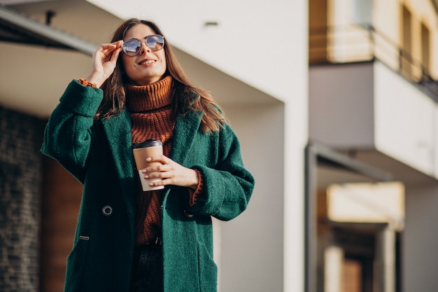 Young woman drinking coffee by the house