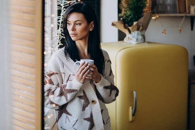 Free Photo young woman drinking coffee by the window