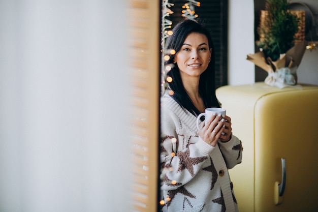 Free Photo young woman drinking coffee by the window