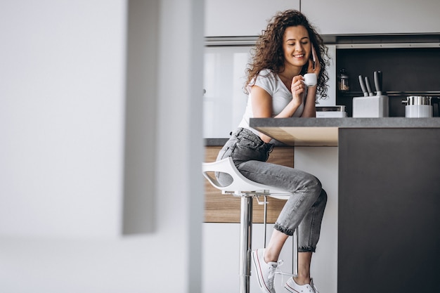 Free photo young woman drinking coffee at the kitchen