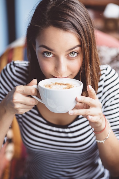 Young woman drinking coffee in urban cafe