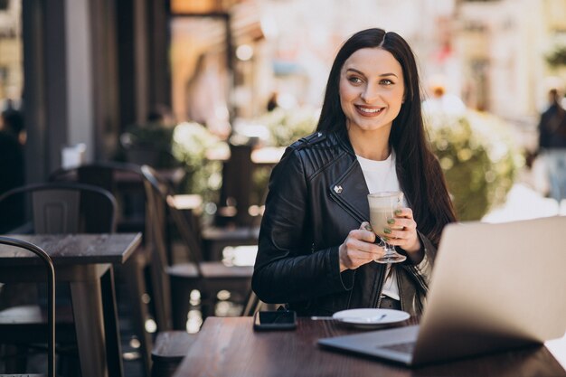 Young woman drinking coffee and working on laptop in a cafe