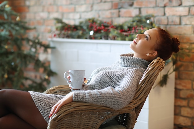 Free photo young woman drinking hot tea on the sofa