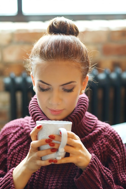 Free photo young woman drinking hot tea on the sofa