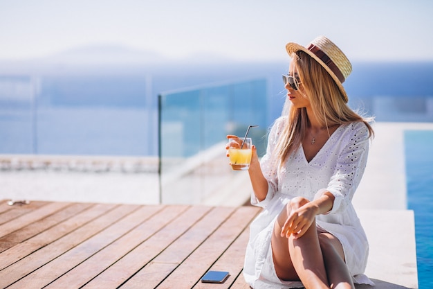 Free photo young woman drinking juice bu the pool