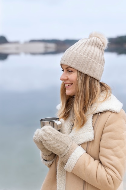 Free photo young woman drinking water by the lake while traveling