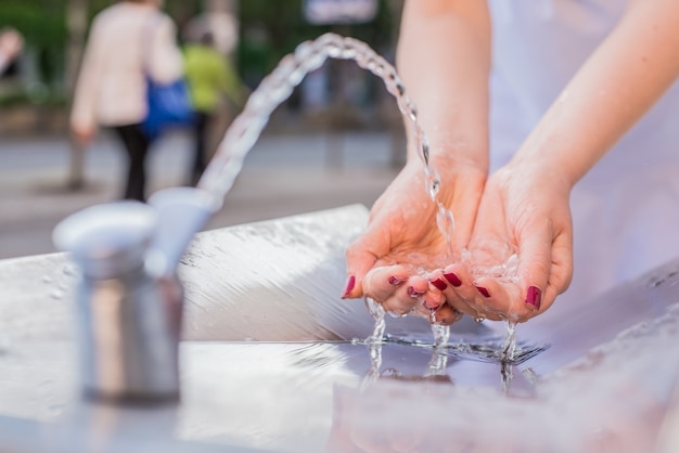 Free photo young woman drinking water from fountain