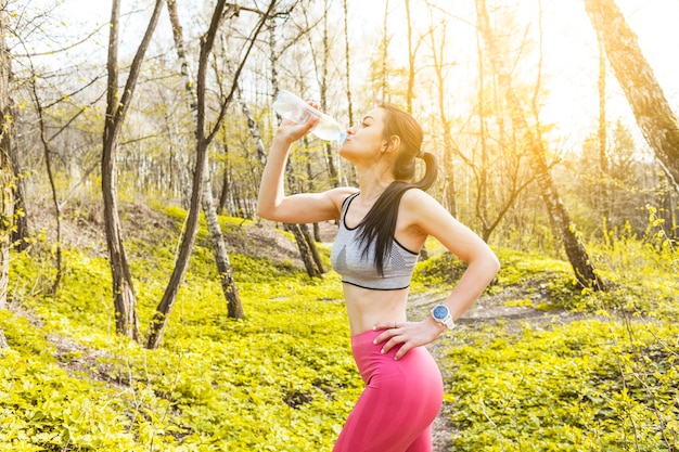 Young woman drinking water in the nature