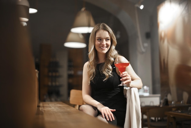 young woman drinks a cocktail in a bar