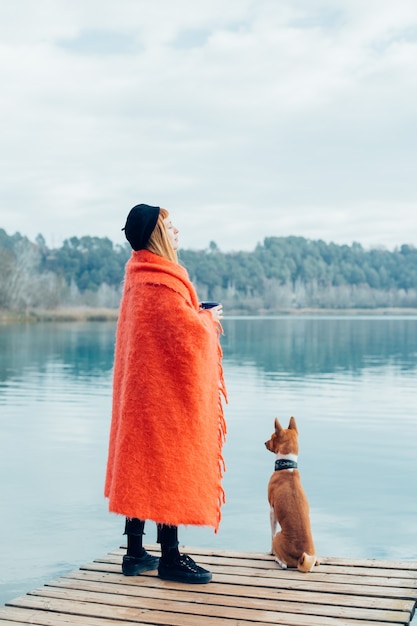 Young woman drinks coffee cup on lake shore